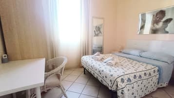A hotel room with a bed, a chair, a desk, and a mirror.