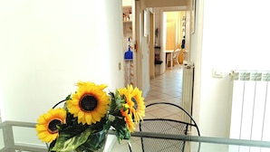 A room with a glass table holding a bouquet of sunflowers, a radiator, and a door leading to another room.