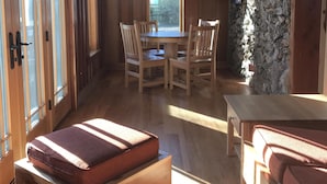 A wooden interior with a dining area, stone wall, and large windows.