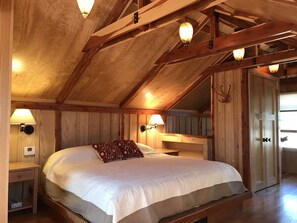 Une chambre à coucher en bois avec un grand lit, deux lampes de chevet et une armoire en bois.