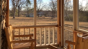 A wooden porch with two chairs and a hanging light fixture.