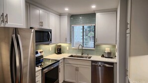 A modern kitchen with stainless steel appliances, white cabinetry, a microwave, a coffee maker, and a dishwasher. - NEWLY RENOVATED, Nicely Equipped, Steps to the Beach, Perfect for Families (Hilton Head Island)