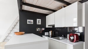 A modern kitchen with white cabinetry, a black backsplash, and a wooden bowl on the counter.