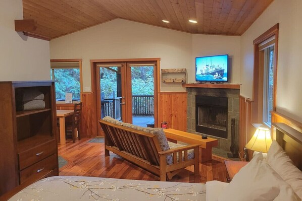 Una habitación acogedora con un banco de madera, chimenea, televisión y un ventanal con vistas a una terraza.