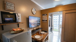 Een kleine keuken met een magnetron, een flatscreen-tv, een klok en een bord met pijlen.