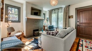 Una sala de estar acogedora con chimenea, un sofá, un sillón y una alfombra.