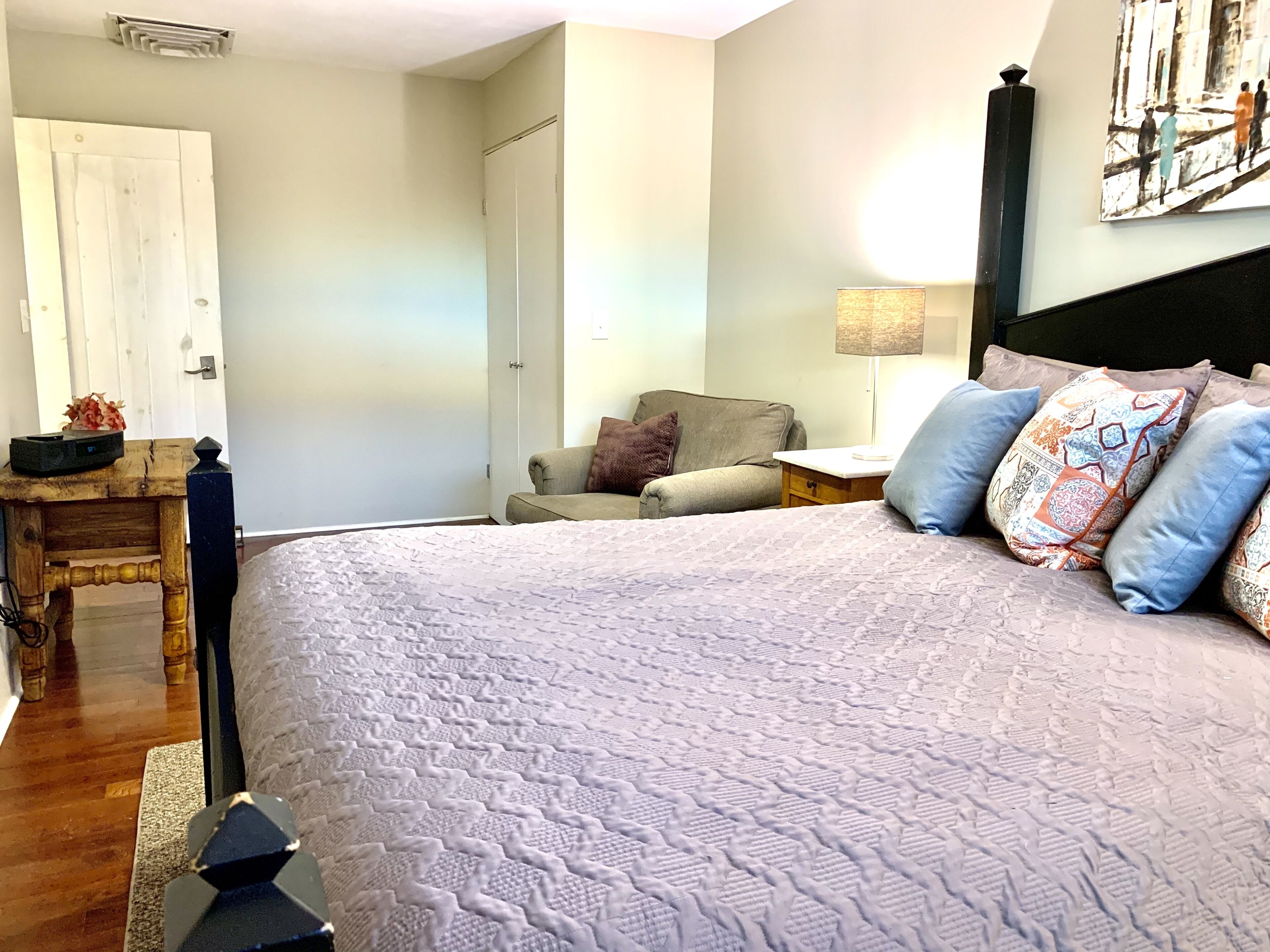 Un dormitorio con una cama grande, una mesita de noche, una silla y una puerta.