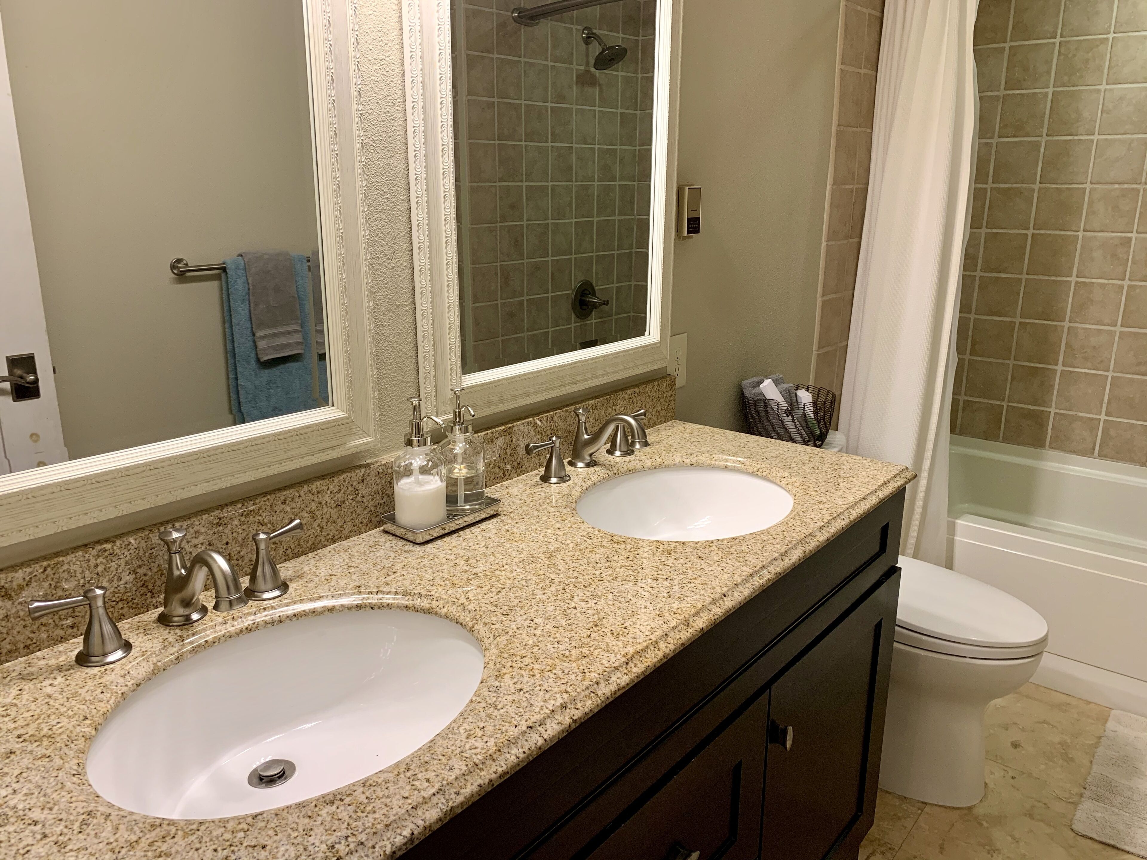 A bathroom with two sinks, a shower, and a toilet.
