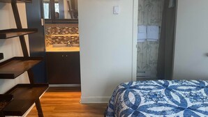 A bedroom with a bed, a bathroom with a sink, and a kitchen area visible through an open door. - Winterplace Condo E306 (Ghent)