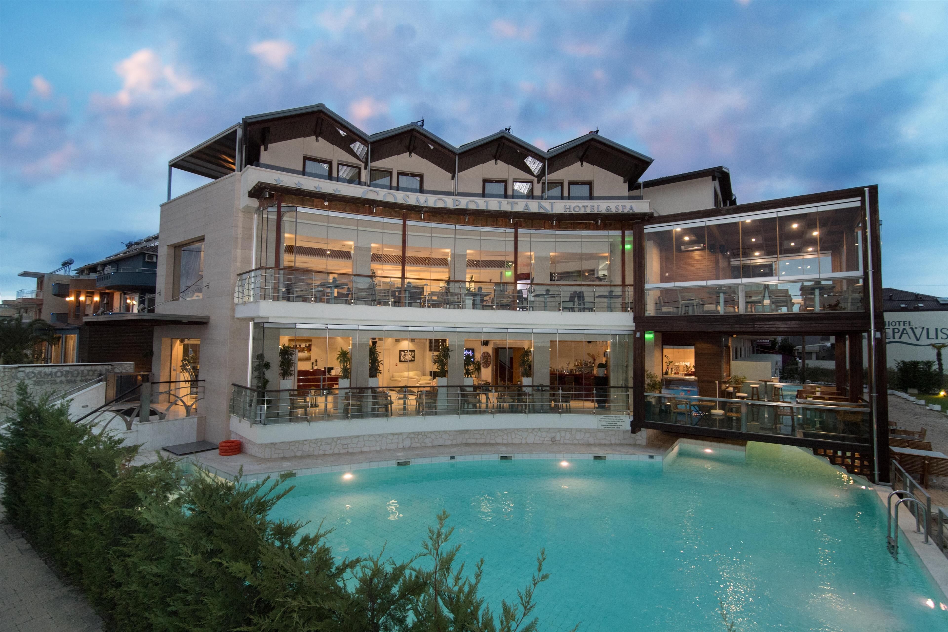 A hotel with a pool, multiple floors, and outdoor seating areas.