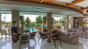 A spacious lobby with a pool view, modern furniture, and large windows. - Cosmopolitan Hotel by GHH (Katerini)