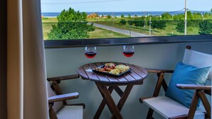 A balcony with a table set for two, featuring a plate of food and two glasses of red wine. - Cosmopolitan Hotel by GHH (Katerini)