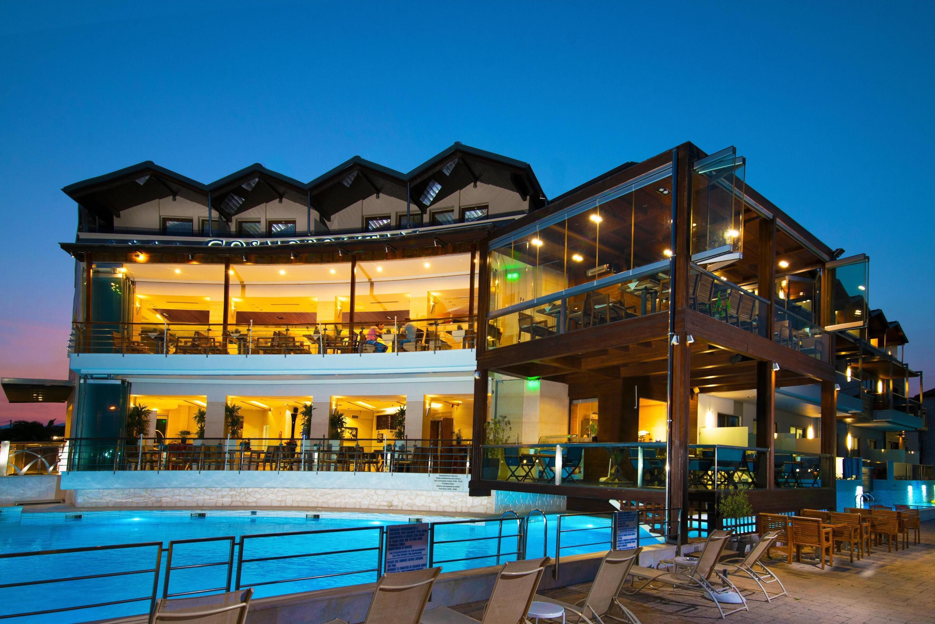 A multi-story hotel with a pool area, outdoor seating, and a restaurant on the upper levels.