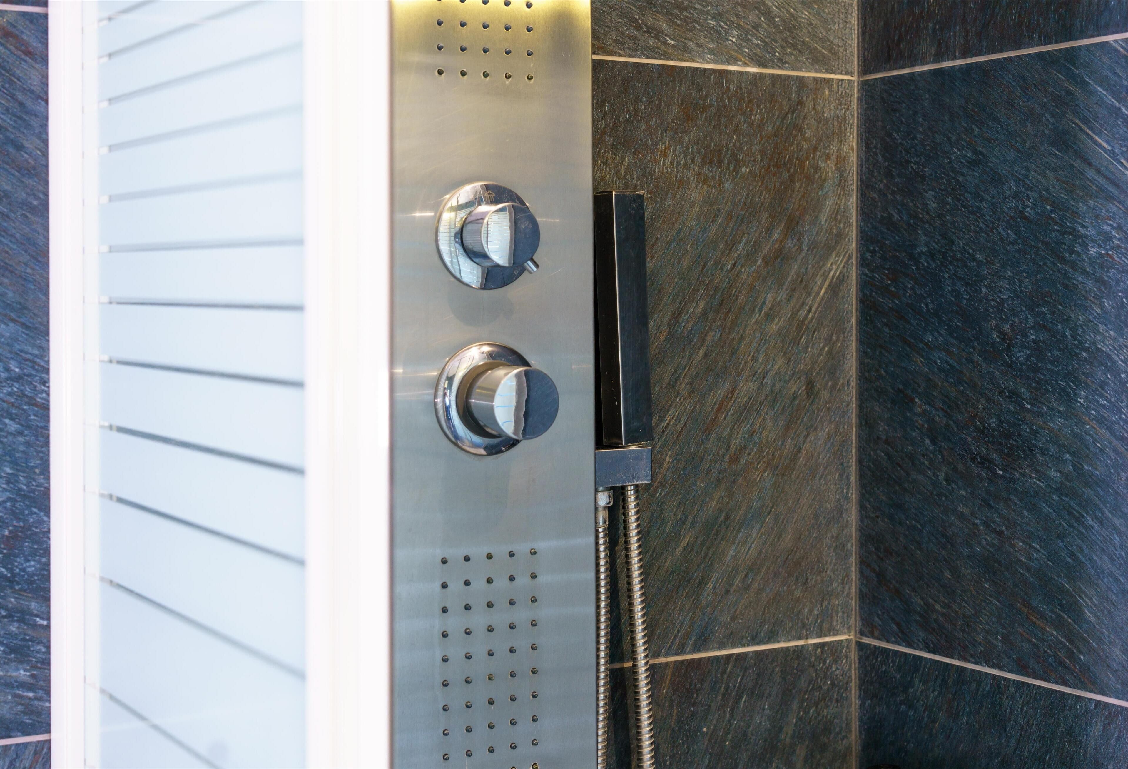 A modern shower with chrome fixtures and a handheld showerhead.