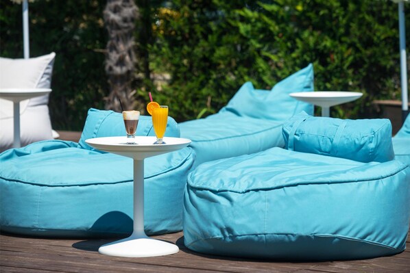 A seating area with blue bean bags and a small table with a drink. - Cosmopolitan Hotel by GHH (Katerini)