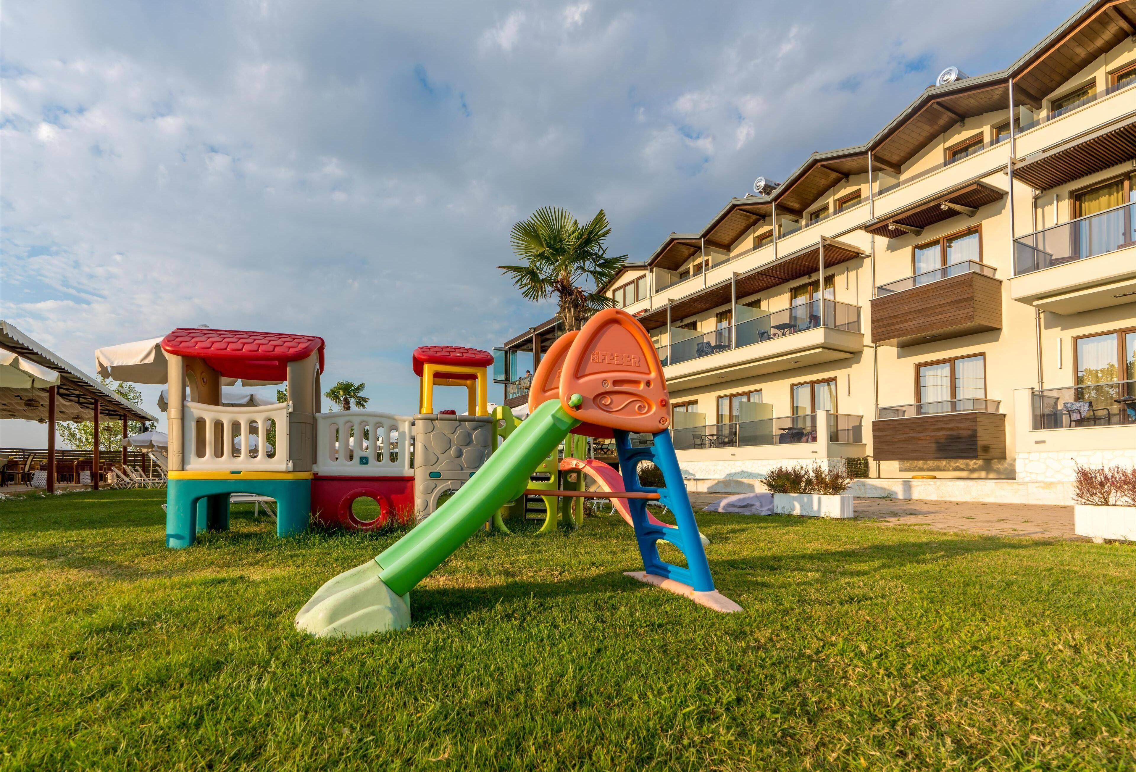 A playground with colorful equipment and a building with balconies in the background.