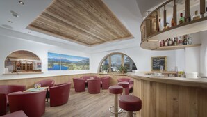 A modern bar area with wooden ceiling, red seating, and a view of the outdoors. - Familotel St. Johanner Hof (Sankt Johann in Tirol)
