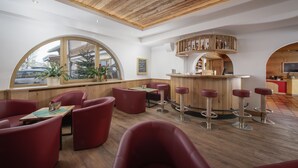 A modern interior with wooden ceiling, red seating, a bar area, and large windows. - Familotel St. Johanner Hof (Sankt Johann in Tirol)