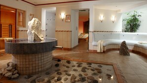 A spa area with a stone sculpture, a hot tub, and a seating area with a view of the room. - Familotel St. Johanner Hof (Sankt Johann in Tirol)