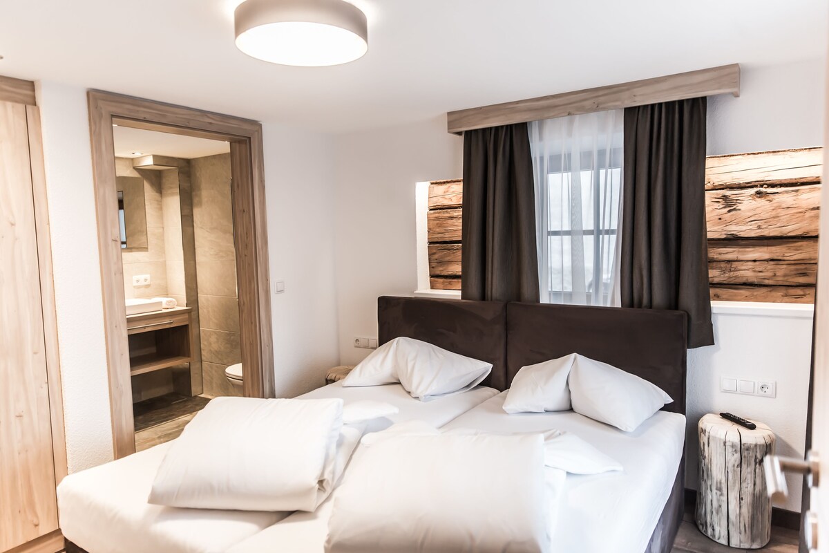 A bedroom with a bed, bedside tables, a mirror, and a window with curtains.