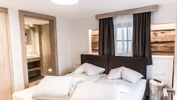 Ein Schlafzimmer mit einem Bett, Nachttischen, einem Spiegel und einem Fenster mit Vorhängen.