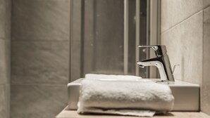 A bathroom with a modern sink, a towel, and a mirror. - A CASA Smaragd (Soelden)