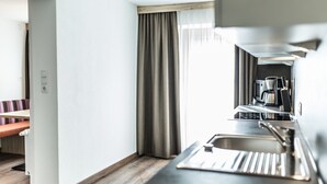 A modern kitchen with a built-in espresso machine, a sink, and a wooden bench in the adjacent room. - A CASA Smaragd (Soelden)