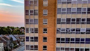 Un hotel de gran altura con un llamativo letrero de 'OX Hotels', varios pisos y un estacionamiento al frente.