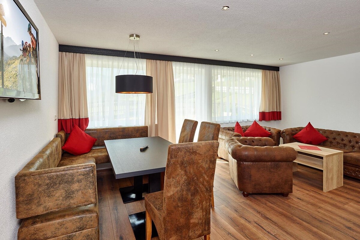 Un salon moderne avec un canapé en cuir marron, une table basse en bois et une table à manger avec des chaises.