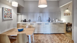 Une cuisine moderne dotée d’un îlot central, de meubles blancs et d’un parquet en bois disposé en chevrons.