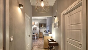 Un couloir mène à une cuisine dont le sol est recouvert de parquet en point de Hongrie, ainsi qu’à un coin repas et à une machine à coudre.