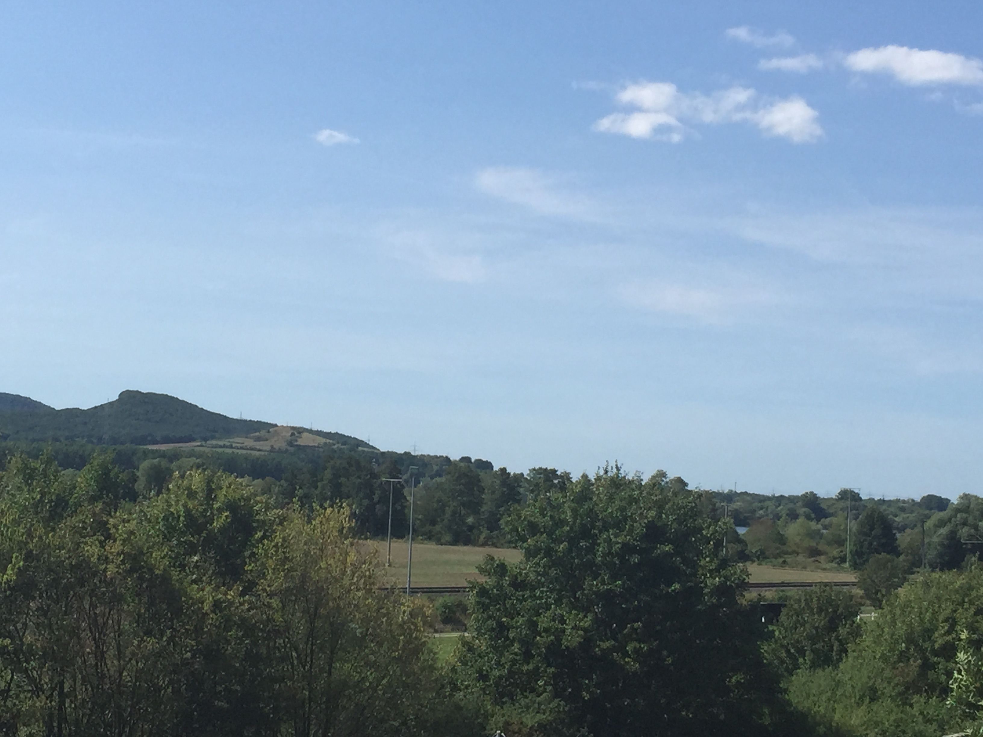 A landscape with a hill, trees, and a bridge.