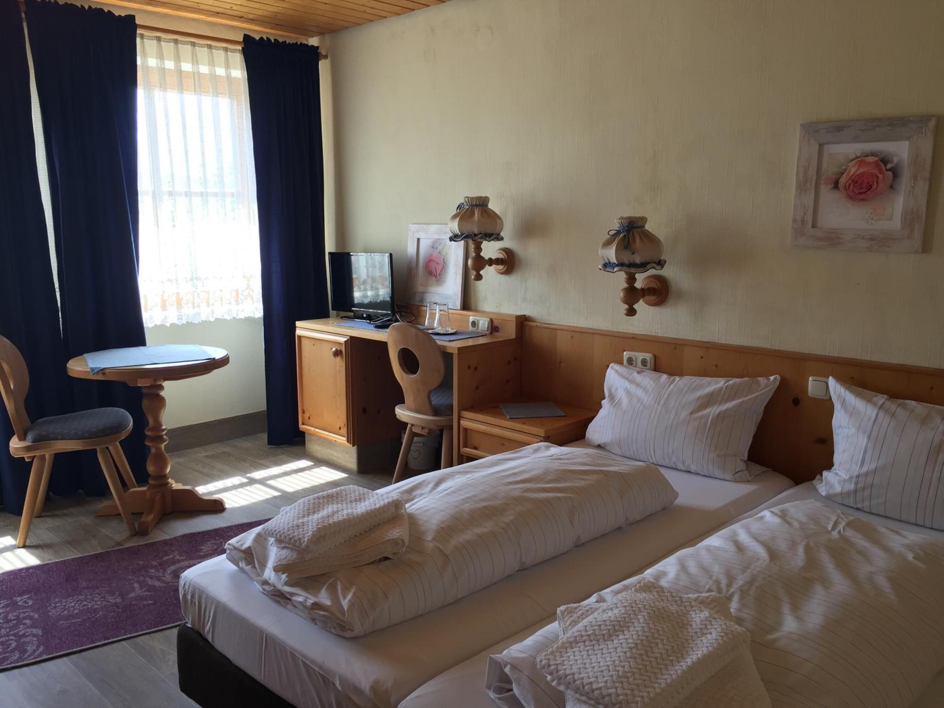 Ein Hotelzimmer mit einem Bett, einem Schreibtisch mit Computer, einem Sessel und einem kleinen Tisch.