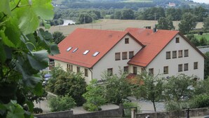 A two-story building with a red-tiled roof, multiple windows, and a garden area in front. - Alte Rose Gasthaus Hotel (Ebelsbach)