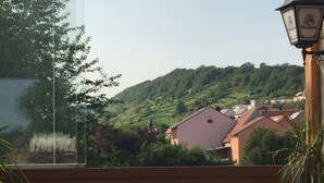 A terrace with wooden chairs and a table, overlooking a hillside with houses and greenery. - Alte Rose Gasthaus Hotel (Ebelsbach)