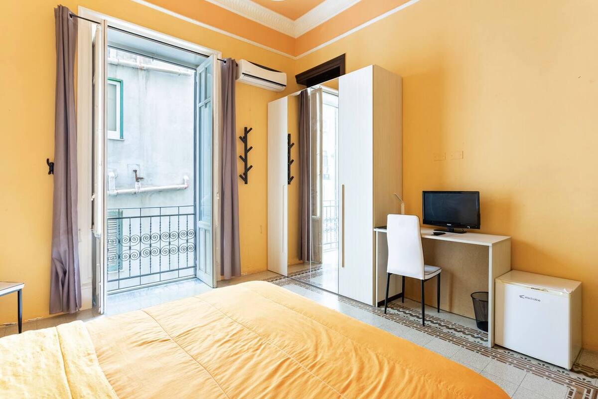 A hotel room with a bed, a desk with a chair, a television, and a mini-fridge.