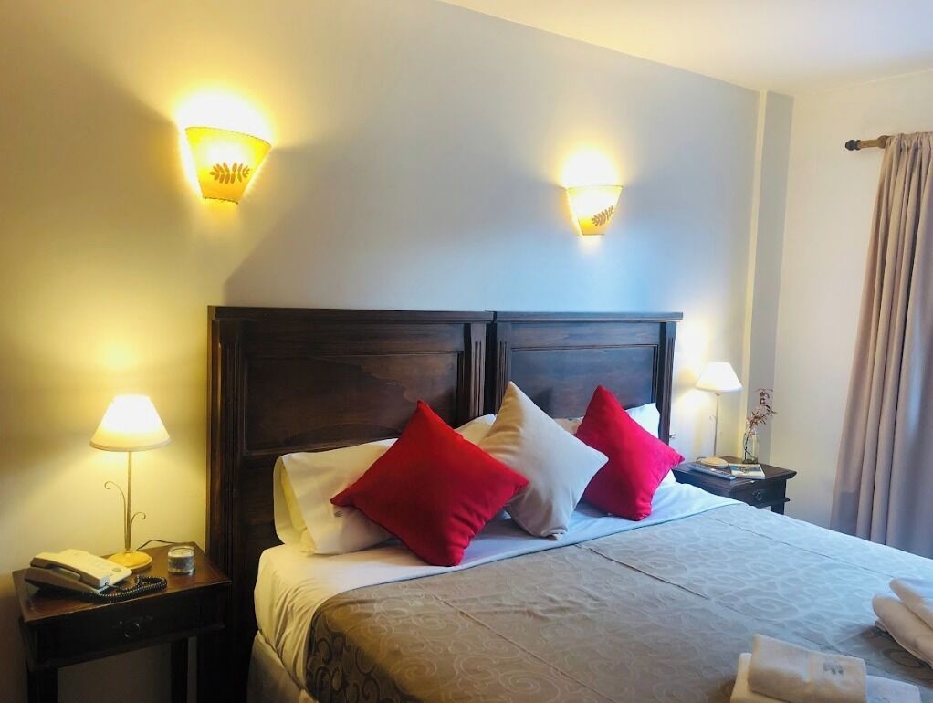A hotel room with a bed, two bedside lamps, a telephone, and a nightstand.