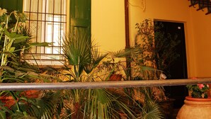 A courtyard with potted plants, a staircase, and a window with green shutters. - Cozy attic among the rooftops of the city (Bologna)