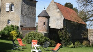 A stone building with a tower, surrounded by greenery and outdoor seating. - cottage in the park of a castle(manor) (Wierre-Au-Bois)