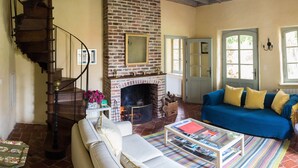A living room with a brick fireplace, a blue sofa, a wooden staircase, and a coffee table. - cottage in the park of a castle(manor) (Wierre-Au-Bois)