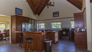 A spacious kitchen with wooden cabinets, a large island, and a ceiling fan.