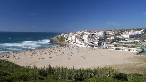 Eine Küstenstadt mit Strand, Gebäuden und blauem Himmel.
