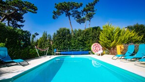 Ein Swimmingpool mit blauen Stühlen und einer Hängematte.