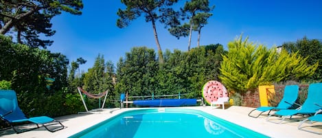 A swimming pool with blue chairs and a hammock.