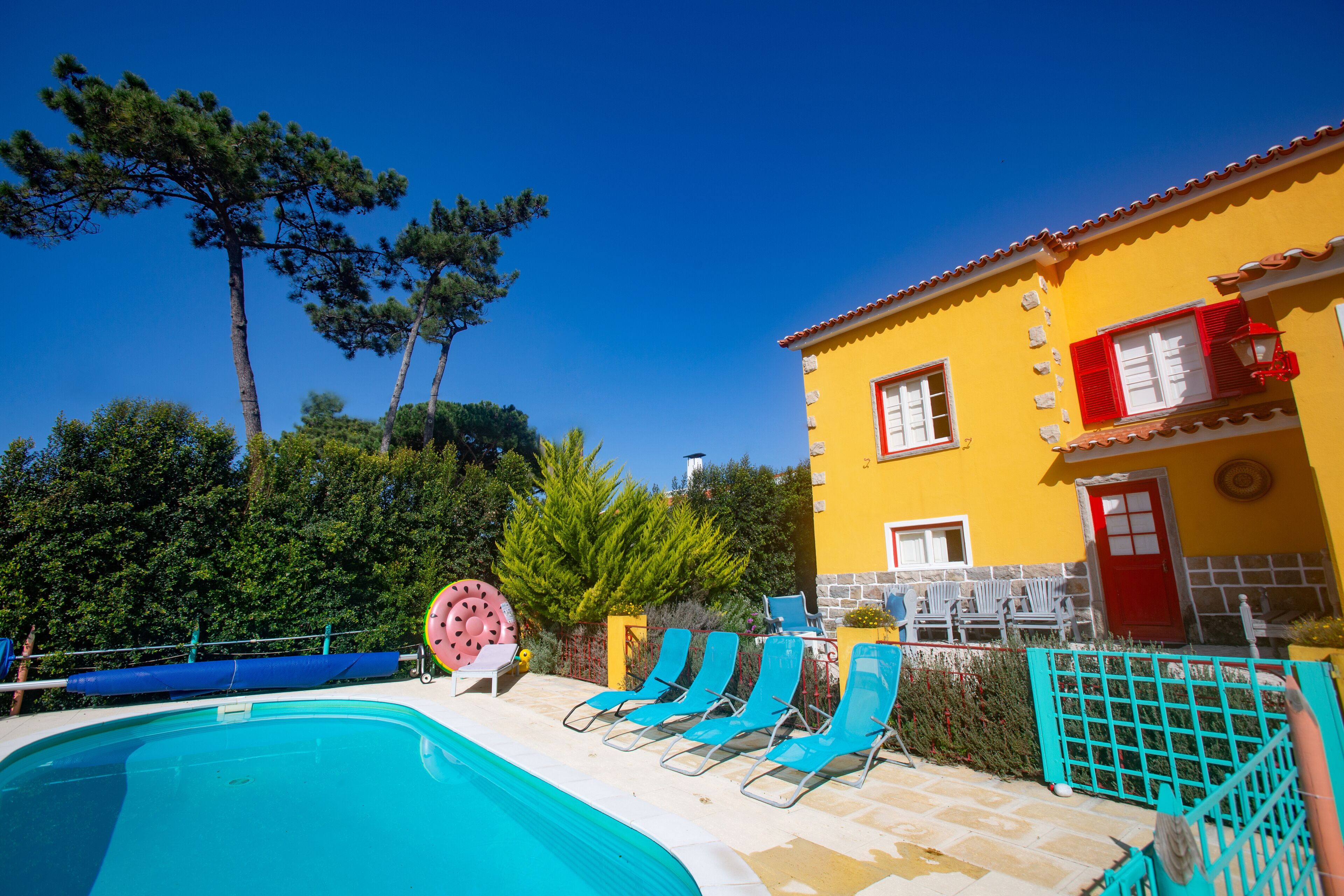 A pool area with blue lounge chairs and a pink watermelon float.