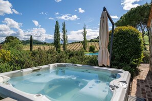 Una vasca idromassaggio in un giardino con piscina e vista sulla campagna.