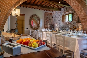 Un comedor con pared de piedra, un espejo y una mesa preparada para comer.