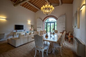 Un salon spacieux avec un plafond haut, une table à manger et une grande fenêtre en arc de cercle.