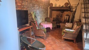 Ein gemütliches Wohnzimmer mit Steinwand, Kamin, Fernseher und bequemen Sitzmöglichkeiten.