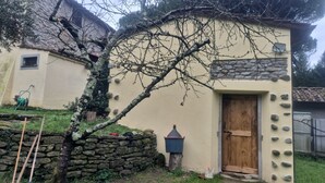 Eine Steinsäule, eine Holztür und ein kleines Fenster an einem Gebäude.